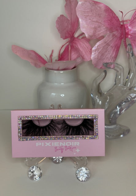 Pink packaging of Pétale lashes displayed with decorative flowers and glass ornament, showcasing feathery, petal-like curl.