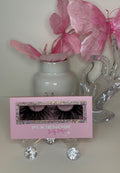 Pink packaging of Pétale lashes displayed with decorative flowers and glass ornament, showcasing feathery, petal-like curl.