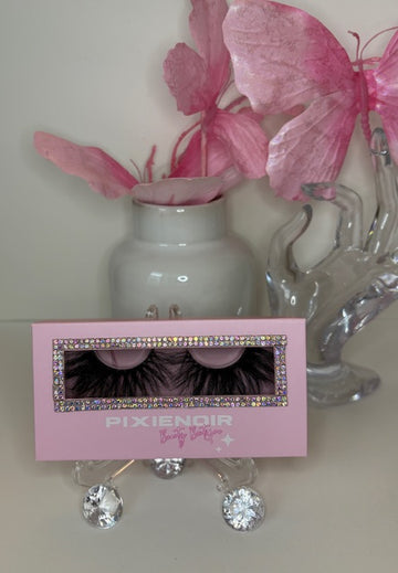 Pink packaging of Pétale lashes displayed with decorative flowers and glass ornament, showcasing feathery, petal-like curl.